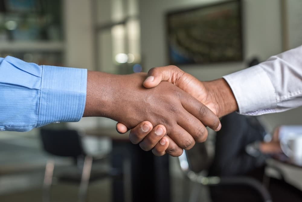 Two people shaking hands over a funding agreement